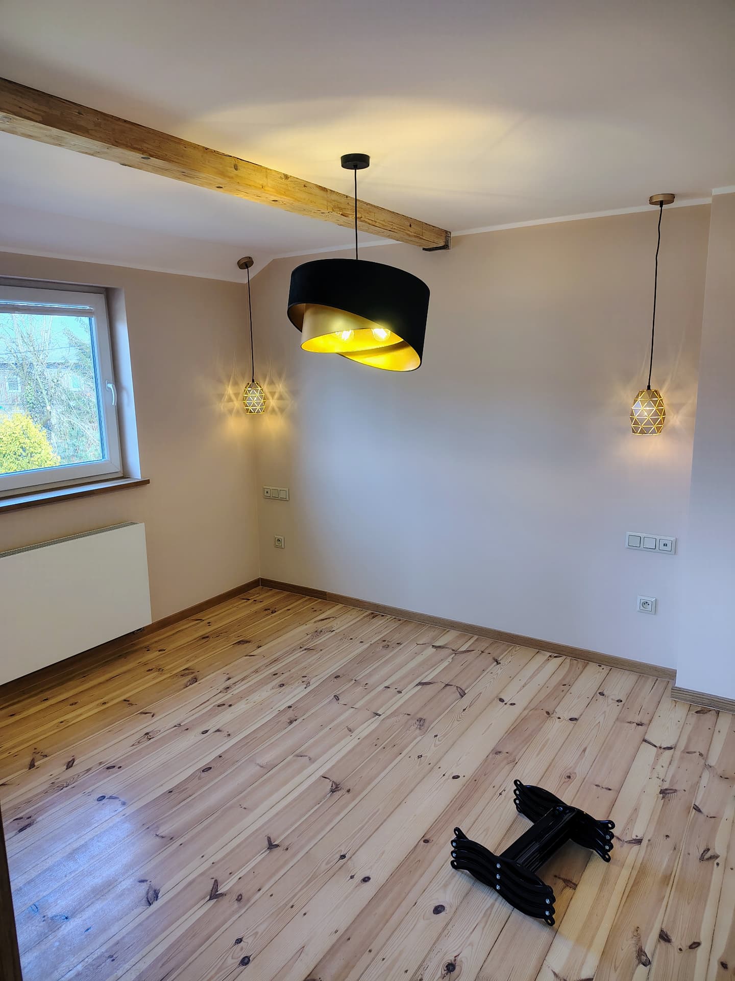 Salon z czarno-złotą lampą wiszącą i oświetleniem punktowym