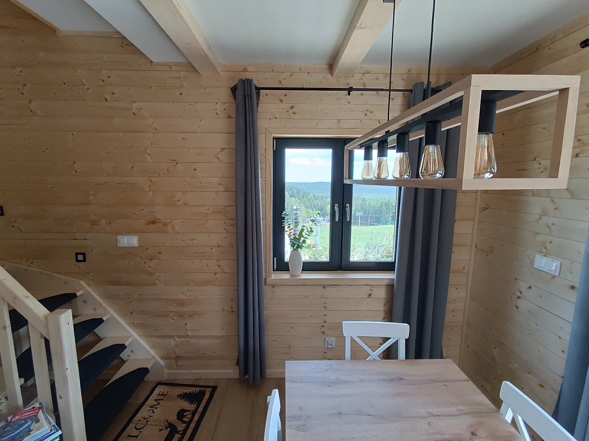 Jadalnia w drewnianym domu z designerską lampą nad stołem